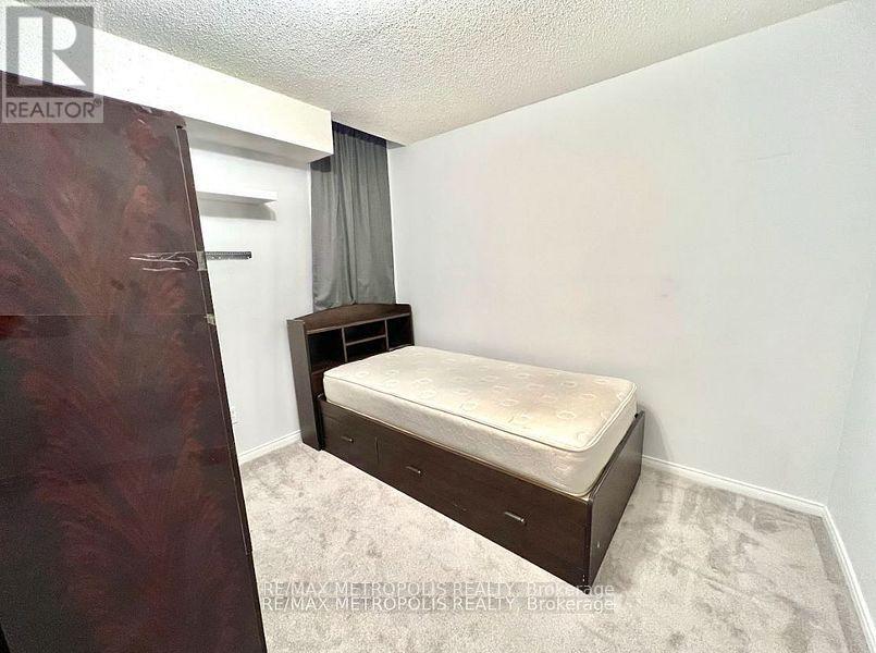 A bedroom with a bed, nightstand, and a window with curtains.