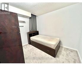 A bedroom with a bed, nightstand, and a window with curtains.