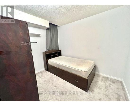 A bedroom with a bed, nightstand, and a window with curtains.