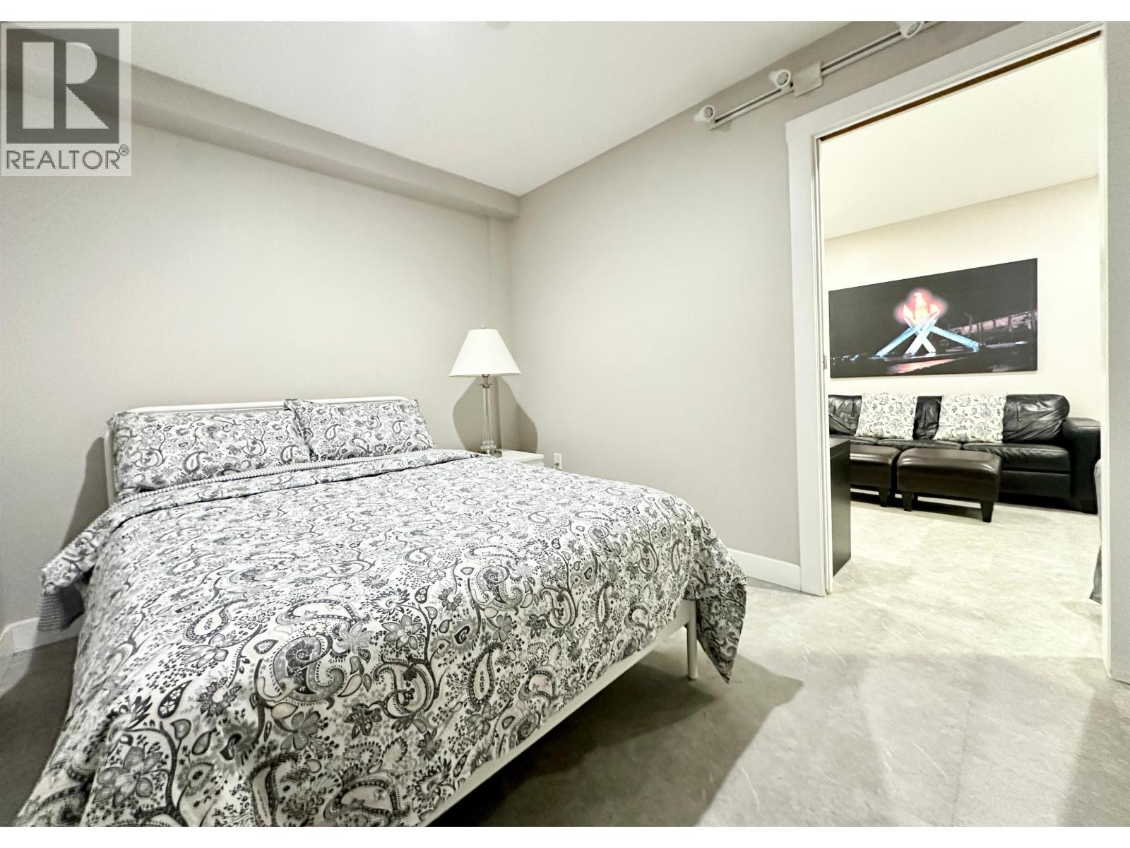 A bedroom with a bed and a couch in the background.