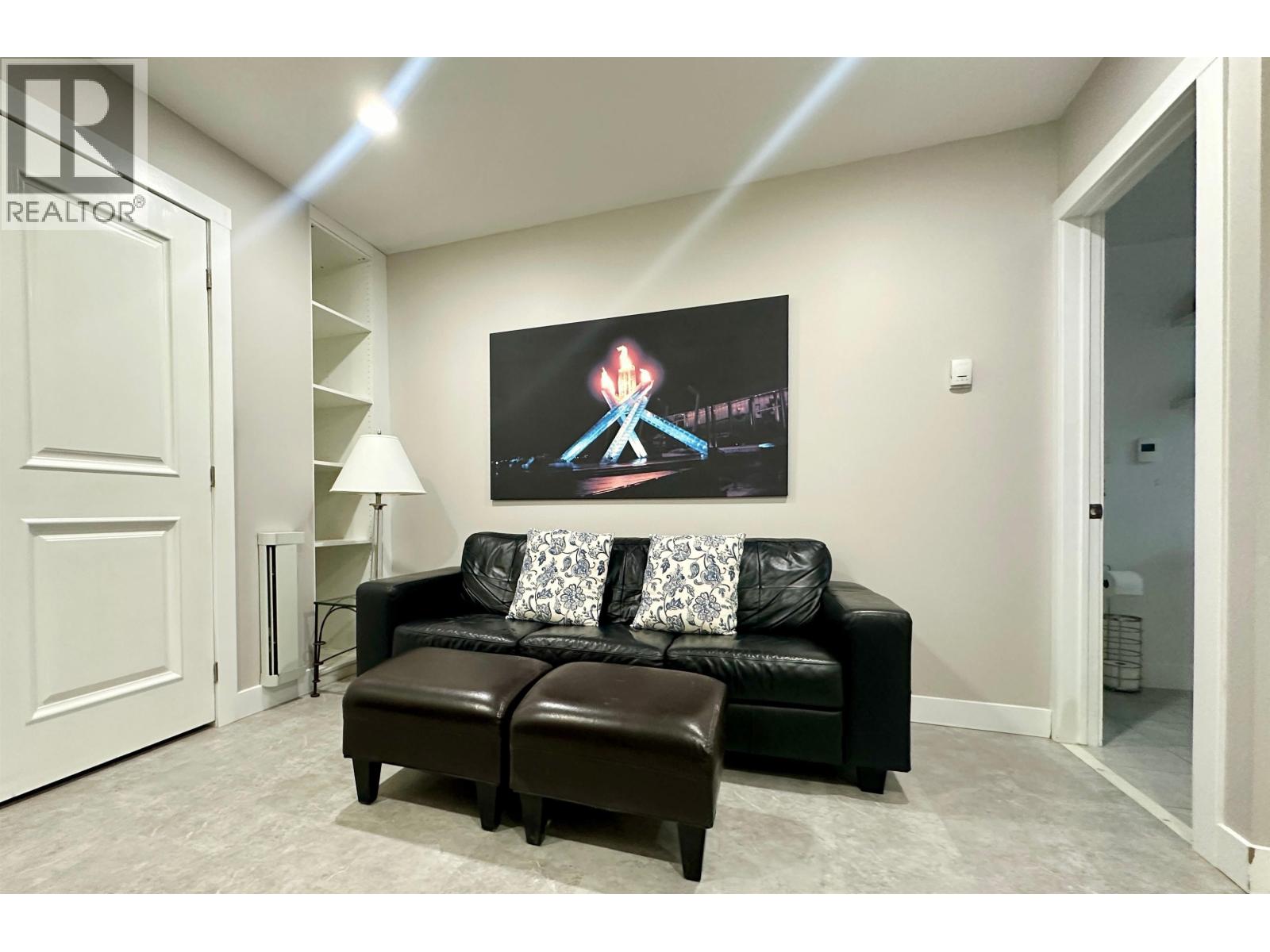 A living room with a black couch and a painting of a person on a skateboard.