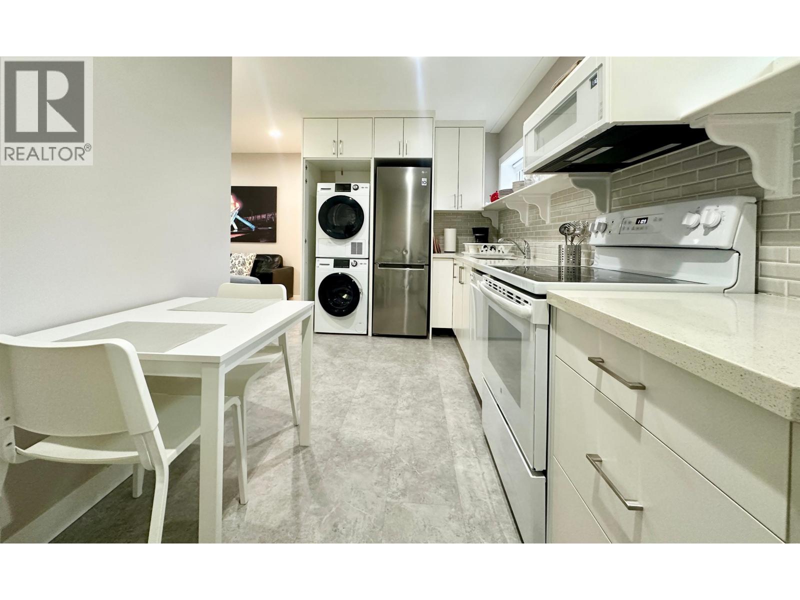 A white chair is in front of a white table in a white kitchen.
