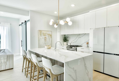 A modern kitchen with white cabinets and a marble countertop.