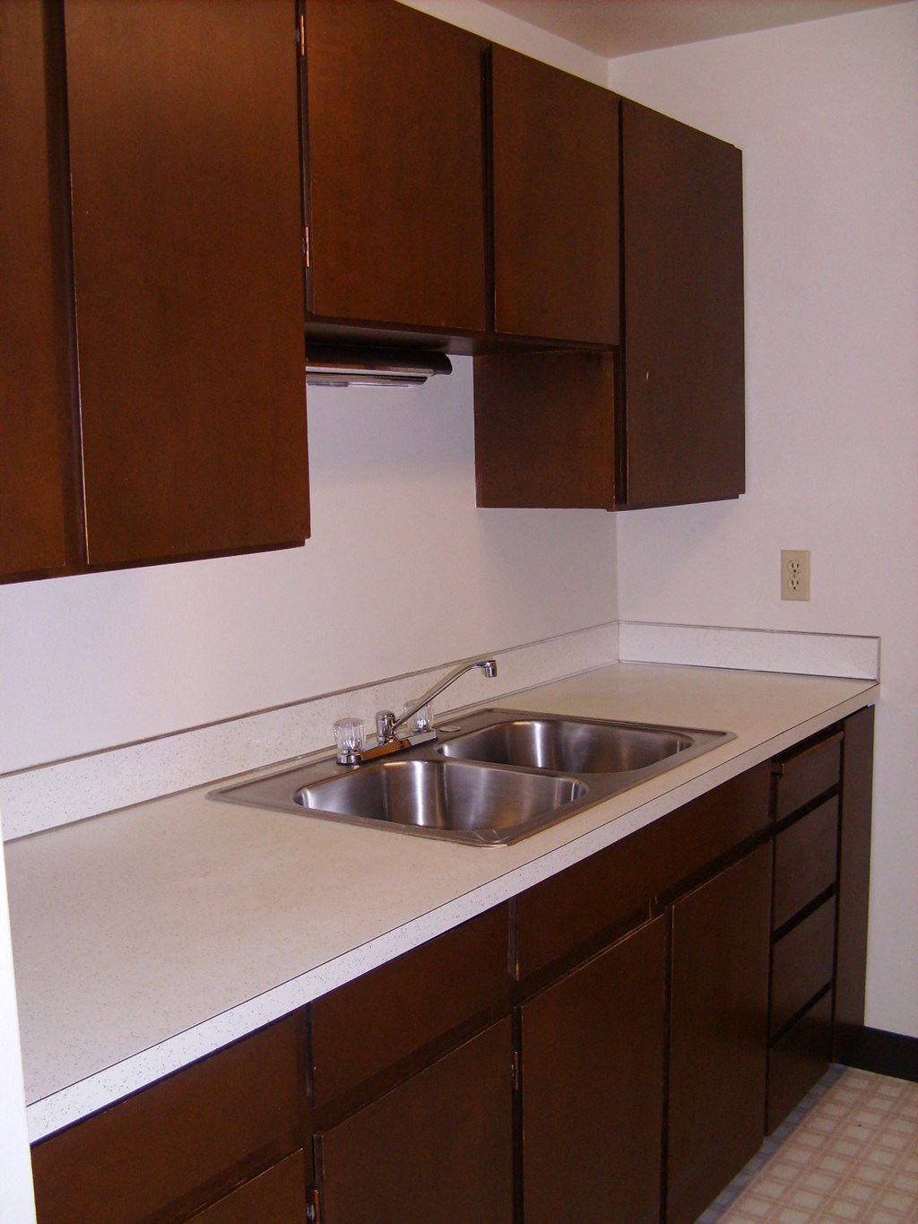 an empty kitchen with a sink and wooden cabinets