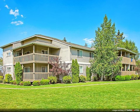 an apartment building with a green lawn and trees