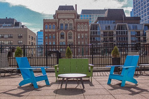 A green bench is in the middle of three blue chairs.