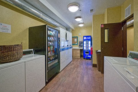 A laundry room with a washer and dryer, a basket, and a vending machine.