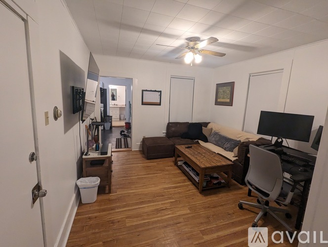 A living room with a brown couch and a white chair.