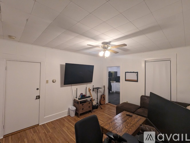 A living room with a television, a couch, a chair, and a guitar.