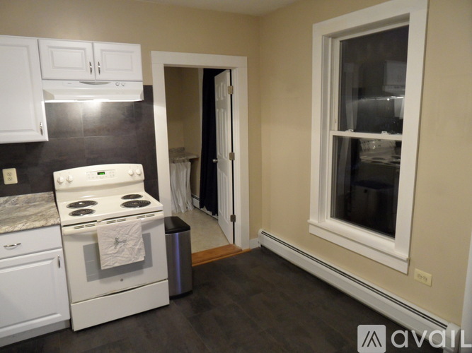 A kitchen with a white stove and cabinets.