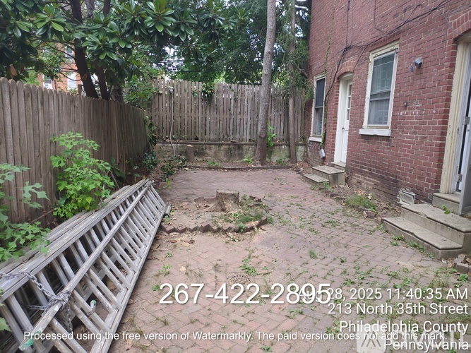 A backyard with a wooden fence and a brick building.