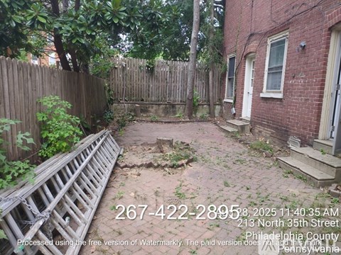 A backyard with a wooden fence and a brick building.