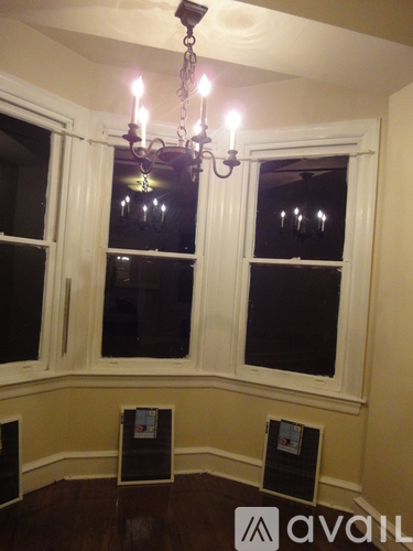 A chandelier hangs over a window in a room.