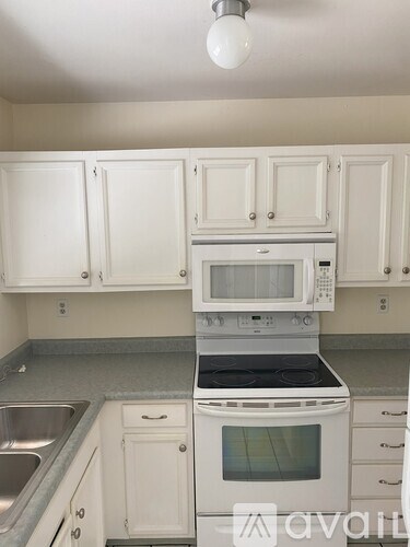 A kitchen with white cabinets and appliances.