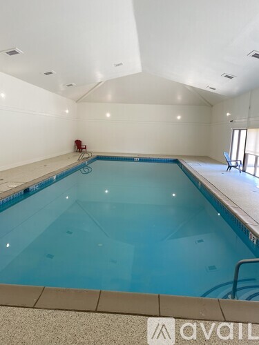 A large indoor swimming pool with a red chair and a logo on the floor.