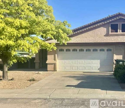 A house with a garage door and a tree in front.