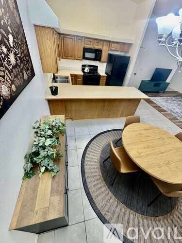 A wooden table and bench are in the foreground of a kitchen.
