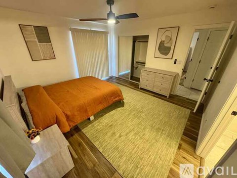 A bedroom with a bed, dresser, and ceiling fan.