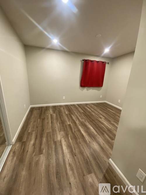 A room with wooden flooring and a red curtain.