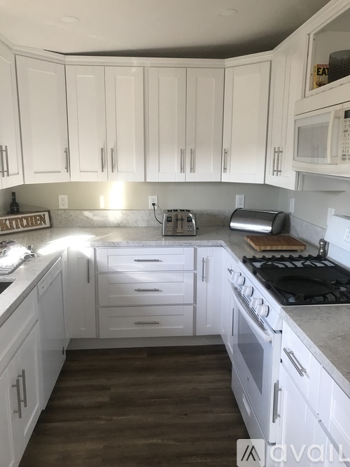 A kitchen with white cabinets and a wooden floor.
