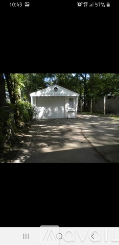 A small white building surrounded by trees.