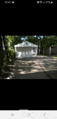 A small white building surrounded by trees.