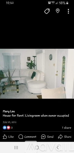 A living room with a white couch and a glass coffee table.