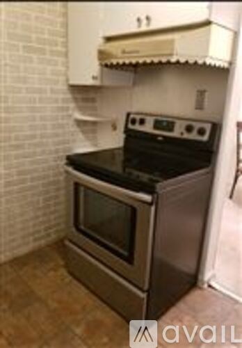 A black stove top oven in a kitchen with a white brick wall.