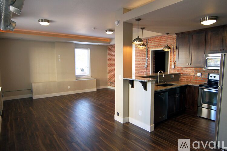 A kitchen with a brick wall and wooden floors.