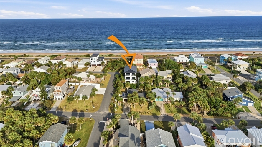 An aerial view of a coastal neighborhood with a prominent orange arrow pointing to a specific house.
