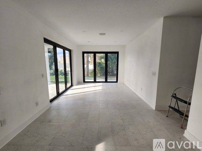 A spacious room with tiled flooring and sliding glass doors leading to a balcony.