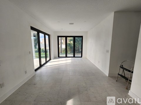 A spacious room with tiled flooring and sliding glass doors leading to a balcony.