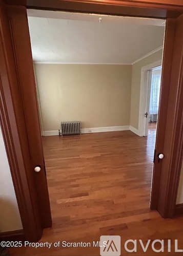 A room with wooden floors and a white ceiling with a heater on the floor.