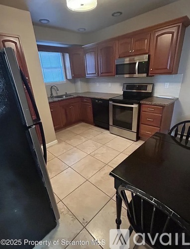 A kitchen with brown cabinets and black appliances.