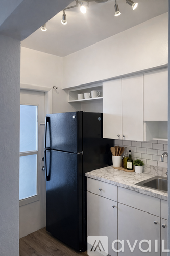 A black refrigerator in a kitchen with white cabinets.