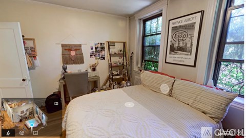 A bedroom with a bed, a desk, and a window.