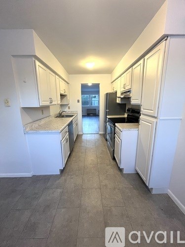 A kitchen with white cabinets and a tiled floor.