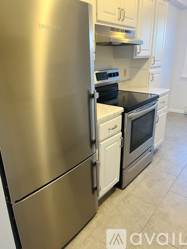 A stainless steel refrigerator with a white oven and microwave in a kitchen.