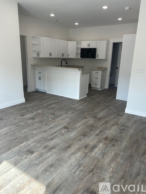 A kitchen with white cabinets and a wooden floor.