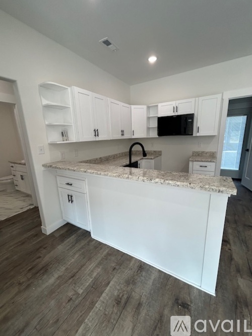 A kitchen with white cabinets and a granite countertop.
