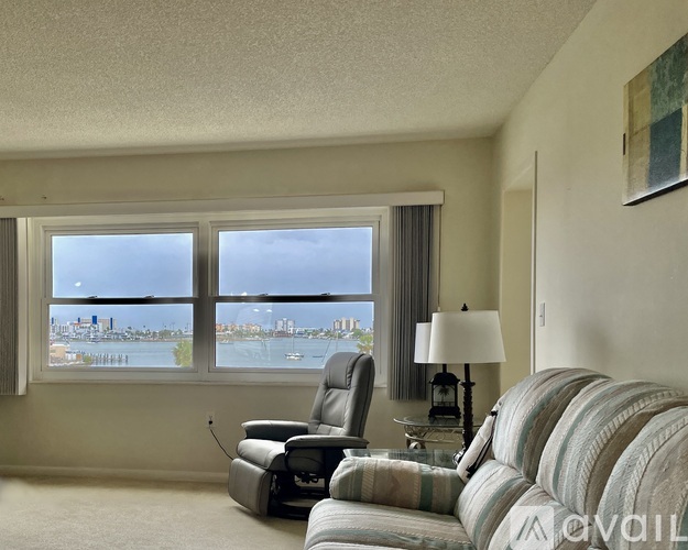 A living room with a striped couch and a chair in front of a window overlooking a city.