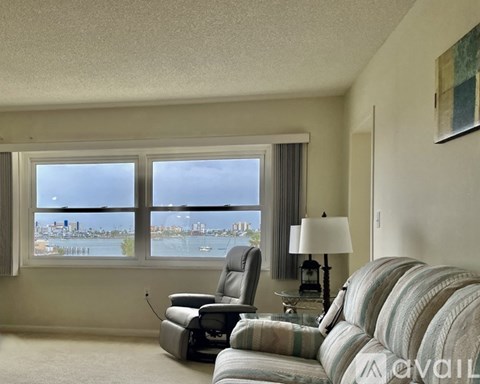 A living room with a striped couch and a chair in front of a window overlooking a city.
