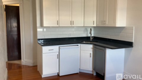 A kitchen with white cabinets and a black countertop.