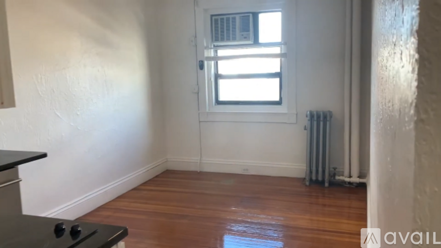 A room with a black stove top oven and wooden flooring.