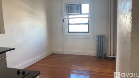 A room with a black stove top oven and wooden flooring.