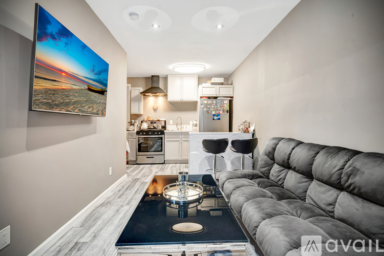 A modern kitchen with a grey sofa and a large painting on the wall.