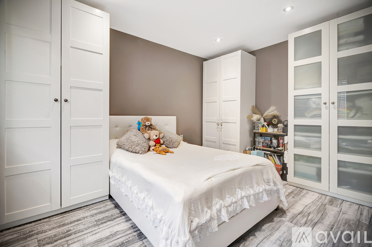 A bedroom with a large bed, a wardrobe, and a shelf with stuffed animals.