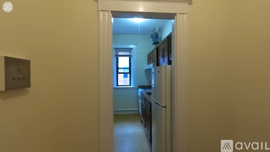 A hallway with a light on and a doorway leading to a kitchen.