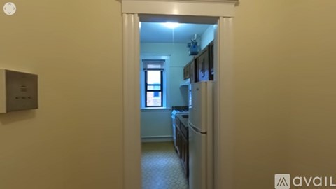 A hallway with a light on and a doorway leading to a kitchen.