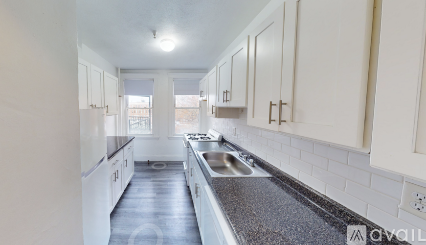 A kitchen with white cabinets and a black countertop.